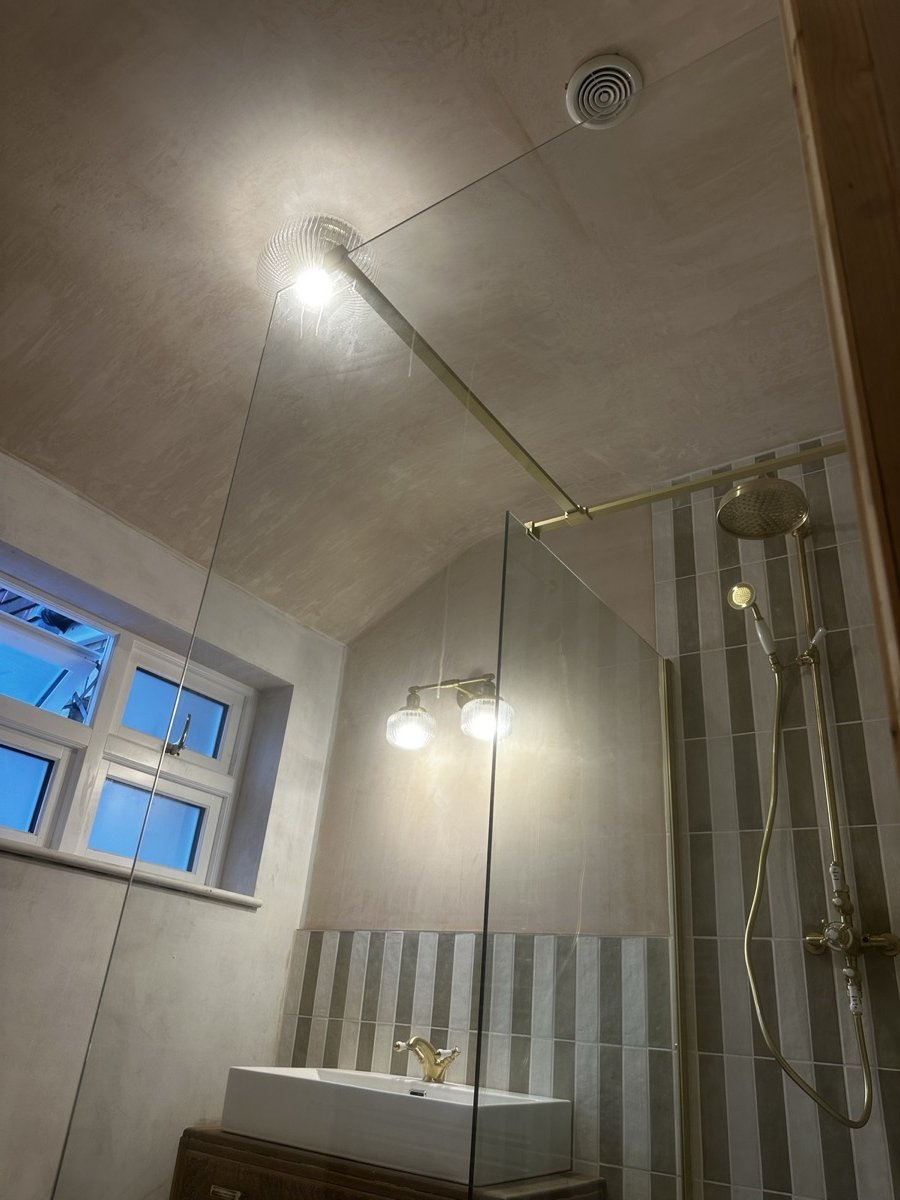 Period bathroom with brass fixtures and striped tiling
