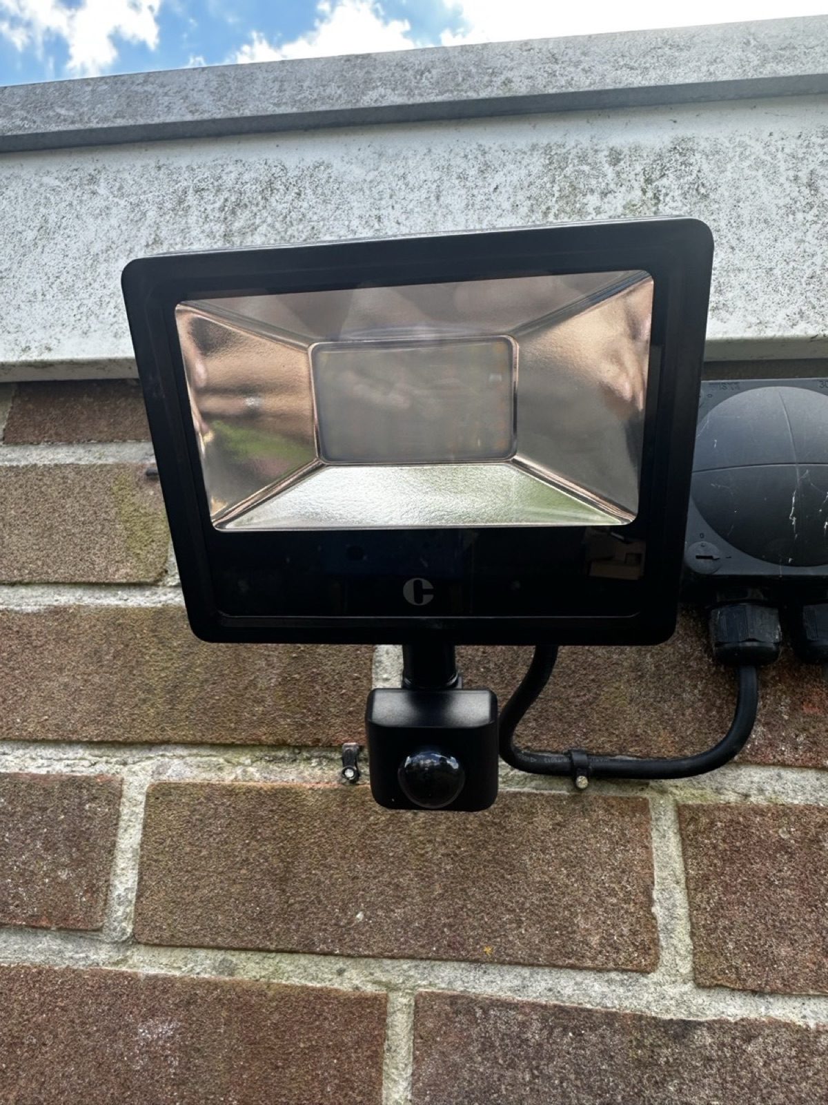 PIR security floodlight installed on stone wall